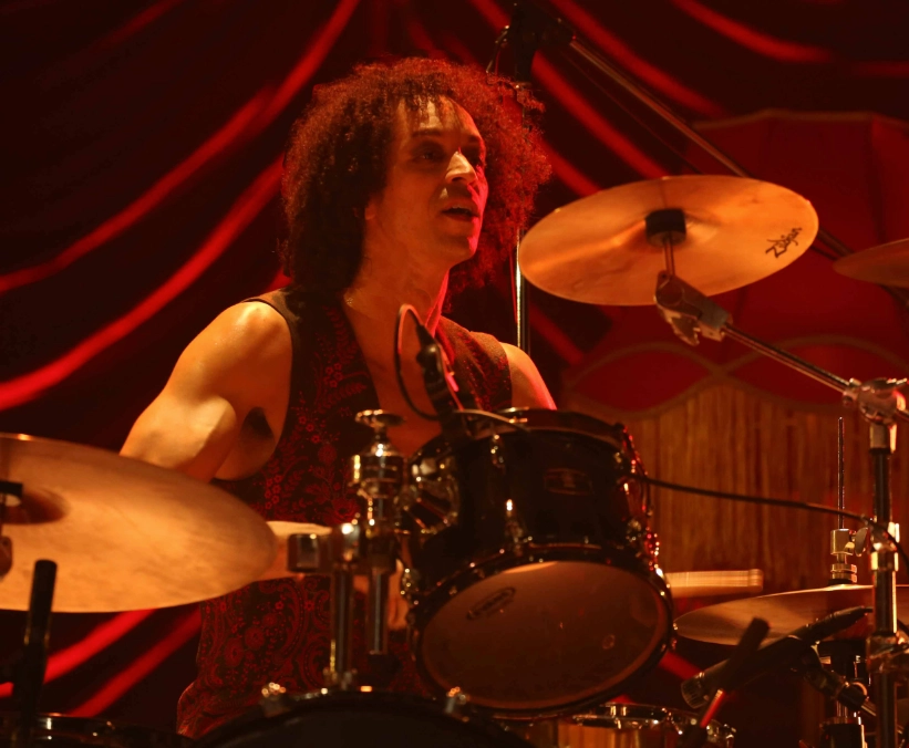 Zack playing drums in dim, red lighting.
